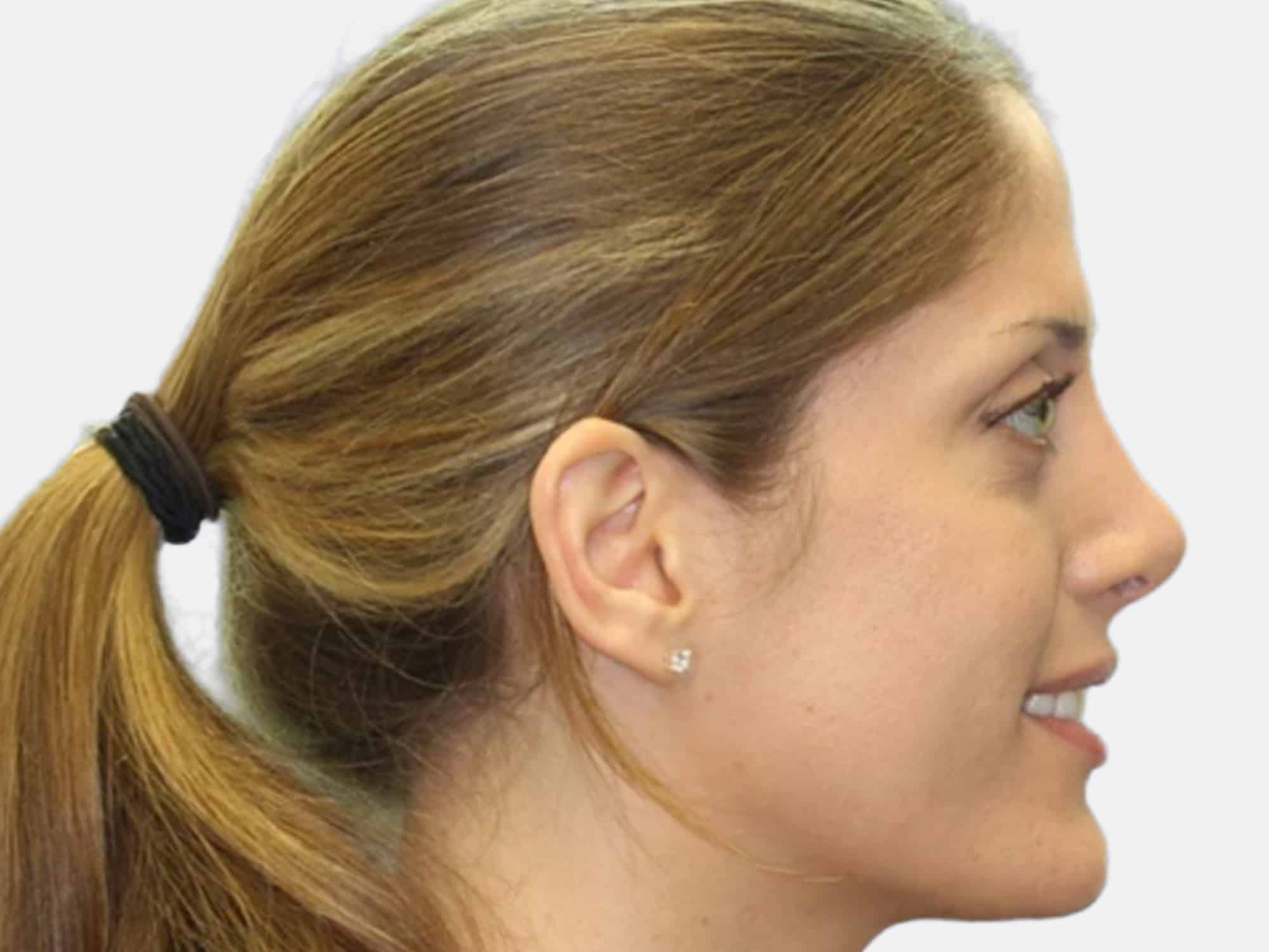 A person with long hair tied back is smiling in profile against a plain white background.